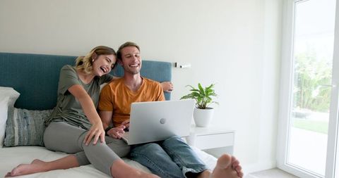 Couple Relaxing on Bed with Laptop for Leisure and Bonding Time