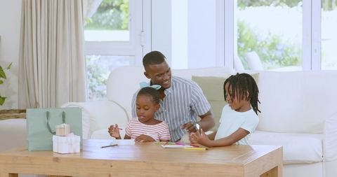 Father Joyfully Watching Children Draw in Cozy Living Room