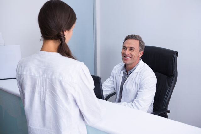 Dentist and female patient engaging in a friendly conversation in a dental clinic. Ideal for use in healthcare, dental care, and medical consultation contexts. Can be used in brochures, websites, and advertisements promoting dental services and patient care.