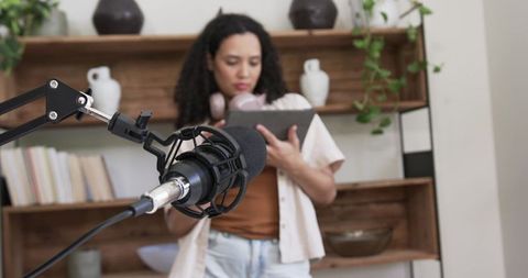 African american woman recording podcast in cozy home studio with boom mic and headphones