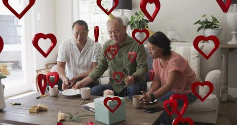 Three adults celebrating birthday gathering sharing cake and coffee on living room sofa