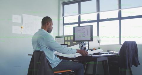 African American Businessman Analyzing Blueprints in Modern Office