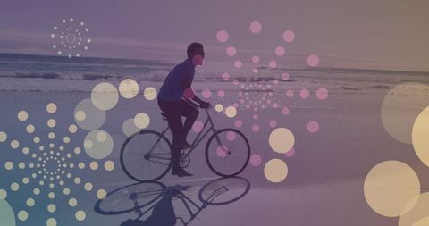 Bicyclist riding along sunny beach with abstract light patterns