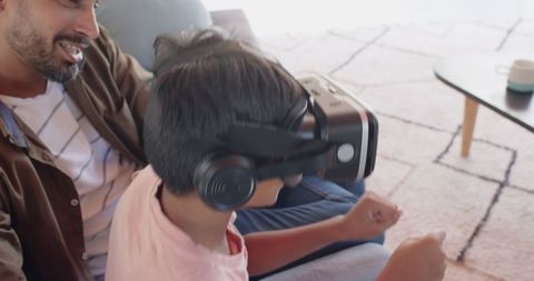 Father and son enjoying vr game on living room sofa