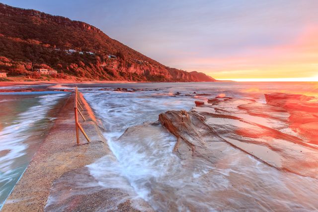 Appreciating gorgeous coastal sunrise scenery, vibrant colors of sunrise over rocky shore offer serene and tranquil feelings, suitable for use in travel promotions and nature photography portfolios.