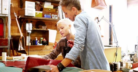 Craftswomen Sharing Ideas Over Leather Material in Workshop
