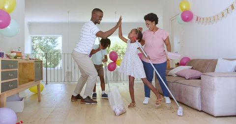 Happy family bonding while cleaning living room after party