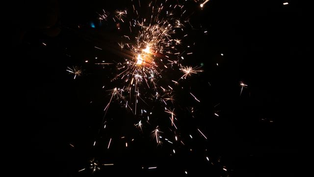 Image showing a close-up of a bright burning sparkler emitting sparks against a black background. Useful for illustrating celebrations, festive events such as New Year or Independence Day, holiday parties, and cheerful atmospheres. Ideal for use in holiday greeting cards, event promotions, and social media posts highlighting festive moments.