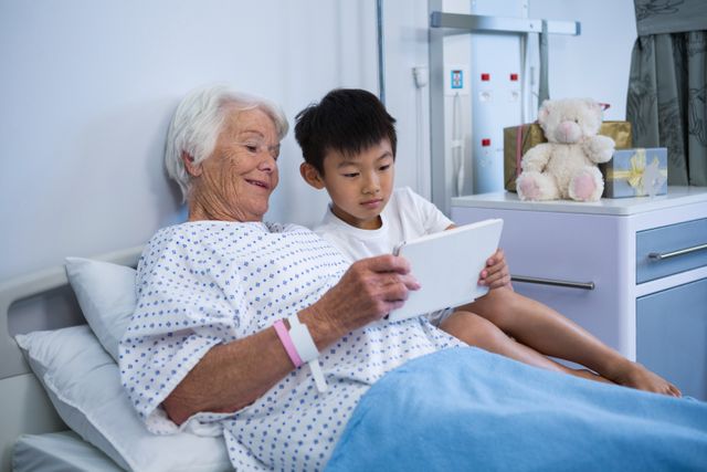 Senior patient and boy holding digital tablet at hospital