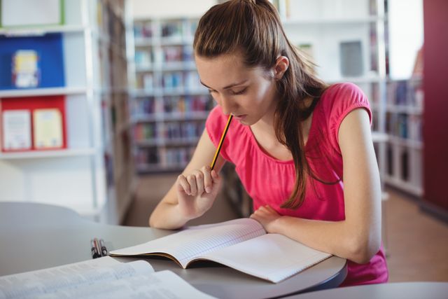 Focused Schoolgirl Studying in Library - Download Free Stock Photos Pikwizard.com