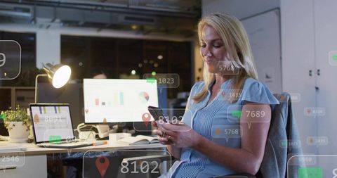 Mature professional checking smartphone at office desk with analytics and charts