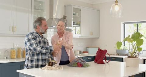 Senior couple organizing kitchen with eco-friendly groceries