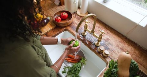 Woman washing vegetables at rustic farmhouse kitchen sink