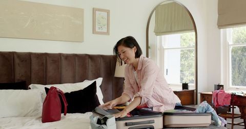 Couple packing suitcase in bright bedroom preparing for travel