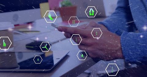 Tapping smartphone showing augmented reality sustainability icons over office desk