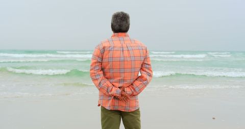 Senior Man Gazing at Ocean on Overcast Day, Reflective Mood