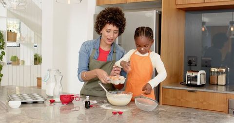 Mother Teaching Daughter to Bake in Home Kitchen