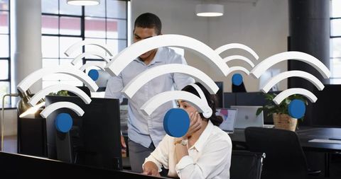 Customer support team working in modern open plan office with wireless connectivity graphics