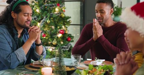 Diverse Friends Celebrating Christmas Meal Praying Together