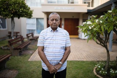 Senior Man Standing Near Building Entrance in Tranquil Setting