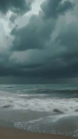 Vertical storm video with dark clouds gathering over ocean and waves crashing on sandy shore