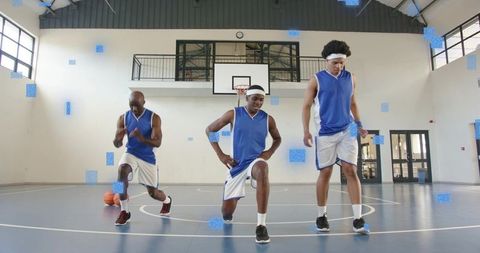 Three basketball players warming up on indoor court stretching pre-game team drill