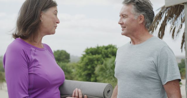 Active senior couple conversing while holding yoga mat outdoors - Download Free Stock Images Pikwizard.com