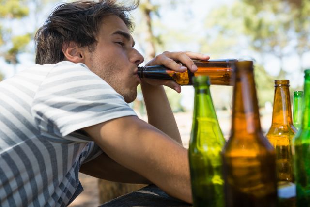 Unconscious man drinking beer from bottle in the park