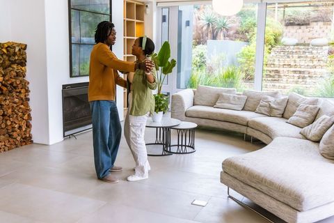 Dancing african american couple in modern living room with glass doors and neutral decor