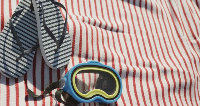 Diving mask and flip flops on beach towel at sunny beach, copy space. Vacations, summer, free time and relaxation.