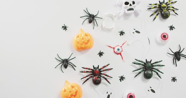 Assorted Halloween-themed decorations spread out on a white background including spiders, pumpkins, a skull, ghosts, and eyeballs. Ideal for promoting Halloween events, festive backdrop displays, party invitations, or seasonal advertisements.