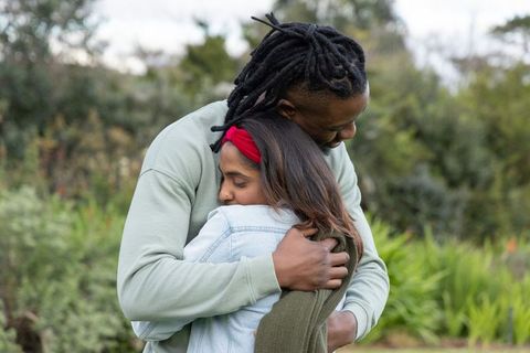 African-american man embracing indian woman in garden hugging tenderly showing intimacy