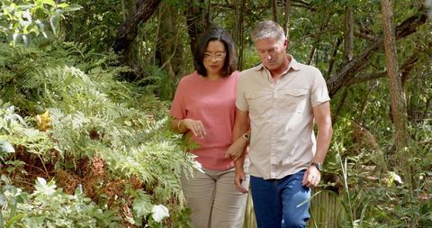 Senior couple walking through serene wooden garden path in nature retreat