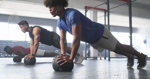 Men Performing Push-Ups on Medicine Balls in Intense Gym Session