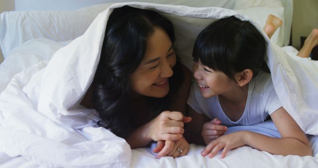 Mother and daughter bonding together underneath blanket in cozy bed - Download Free Stock Images Pikwizard.com