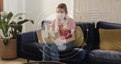 Remote work woman typing on laptop at home on navy sofa with data visualization overlay