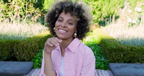 Young Woman Smiling in Peaceful Garden with Sunlight