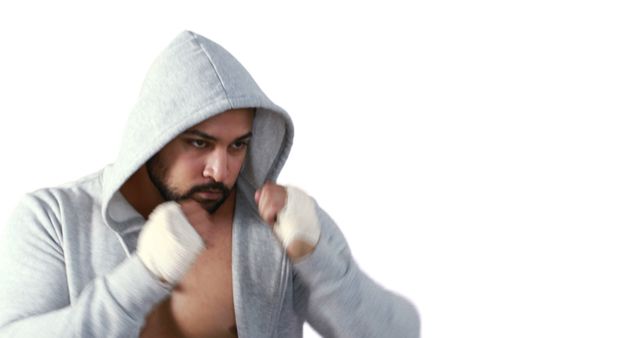 Man wearing a gray hoodie intensely shadow boxing with wrapped hands. Useful for fitness campaigns, sports training guides, martial arts promotions, or athletic gear advertisements, emphasizing focus, strength, and physical conditioning.