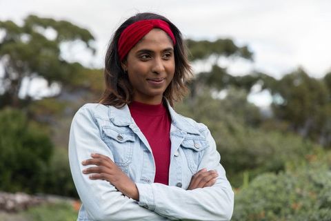 Confident indian woman standing with arms crossed wearing red headband and denim jacket