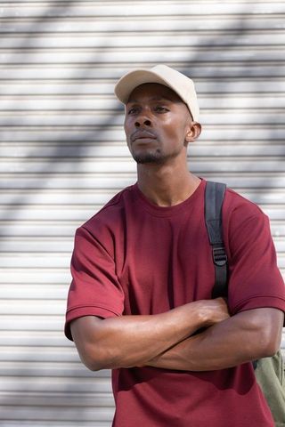 Urban portrait african american man standing with crossed arms, looking up rollup shutter