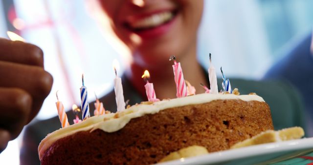 Happy person celebrating birthday with a beautifully decorated cake having lit candles. Perfect for use in birthday cards, advertisements for bakeries, celebration newsletters, and party planning materials highlighting joy and special occasions.