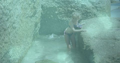 Child exploring rocky shoreline for beachside adventure