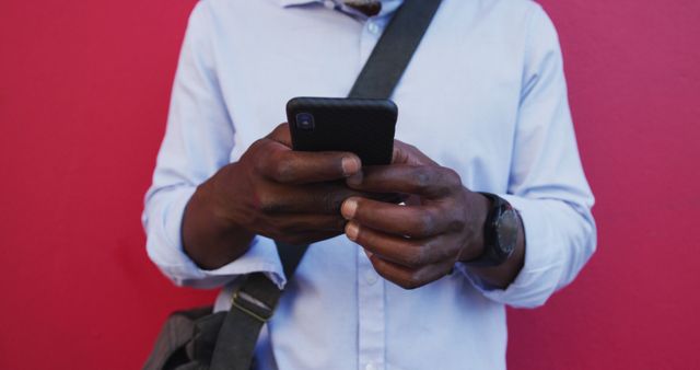 Man Texting on Smartphone Against a Bright Red Wall - Download Free Stock Images Pikwizard.com