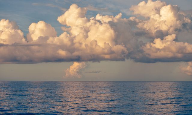Beautiful scene capturing a calm ocean with dramatic cloud formations in the sky during daylight. Ideal for travel blogs, nature websites, meditation and relaxation content, or as a stunning background image.
