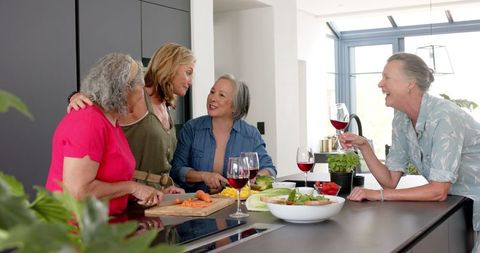 Senior Friends Enjoying Wine in Modern Kitchen