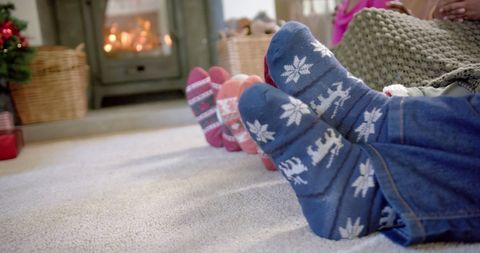 Warm family relaxing in cozy socks by fireplace