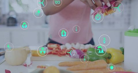 Woman chopping fresh vegetables in home kitchen with eco tech icons overlay for sustainable cooking