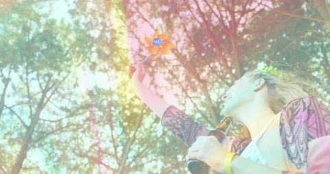 Sunlit festival moment raising pinwheel holding bottle wearing boho kimono floral crown