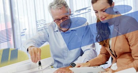 Senior mentor pointing as young professional reviews prototype and analytics on tablet