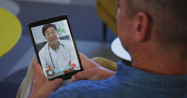 This image depicts a senior male patient engaging in a video call with a male doctor via a tablet. The doctor, wearing a white coat and stethoscope, is providing remote medical consultation. Suitable for illustrating concepts of telemedicine, remote healthcare, or usage of technology in modern healthcare. Ideal for blogs, healthcare websites, telehealth service promotions, and digital health technology advertisements.